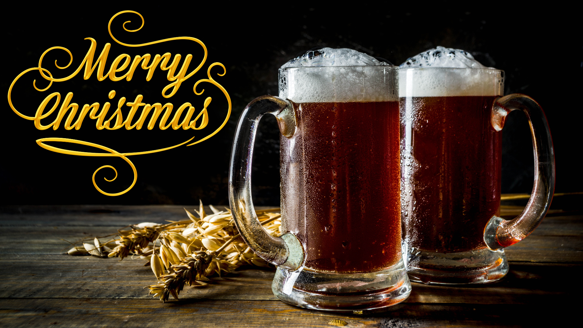 Two mugs of foaming dark Christmas beer on a wooden table, with the words Merry Christmas in gold lettering beside them.